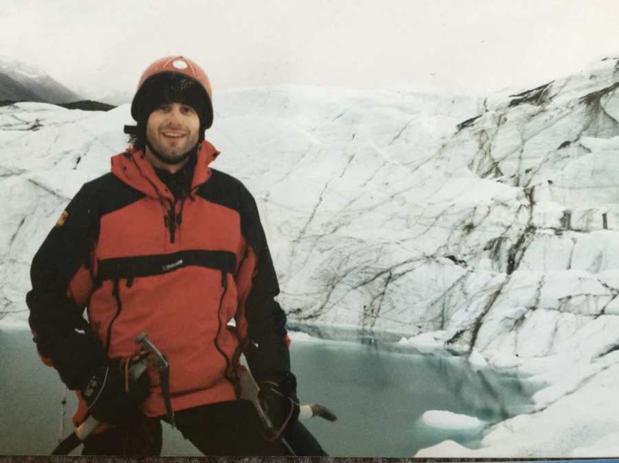 Steven in a red jacket and helmet in front of a glacier