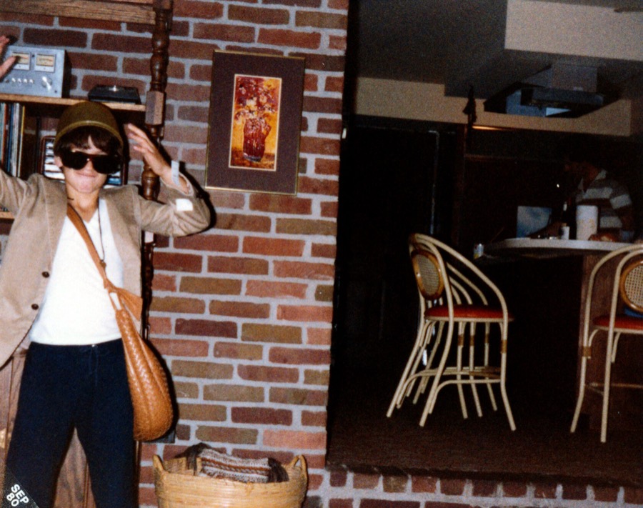 A family snapshot: a woman in sunglasses and a hat striking a pose in a restaurant