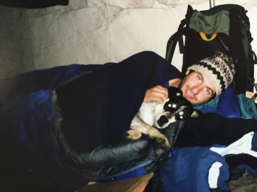 Steven in a sleeping bag inside a tent with a small dog