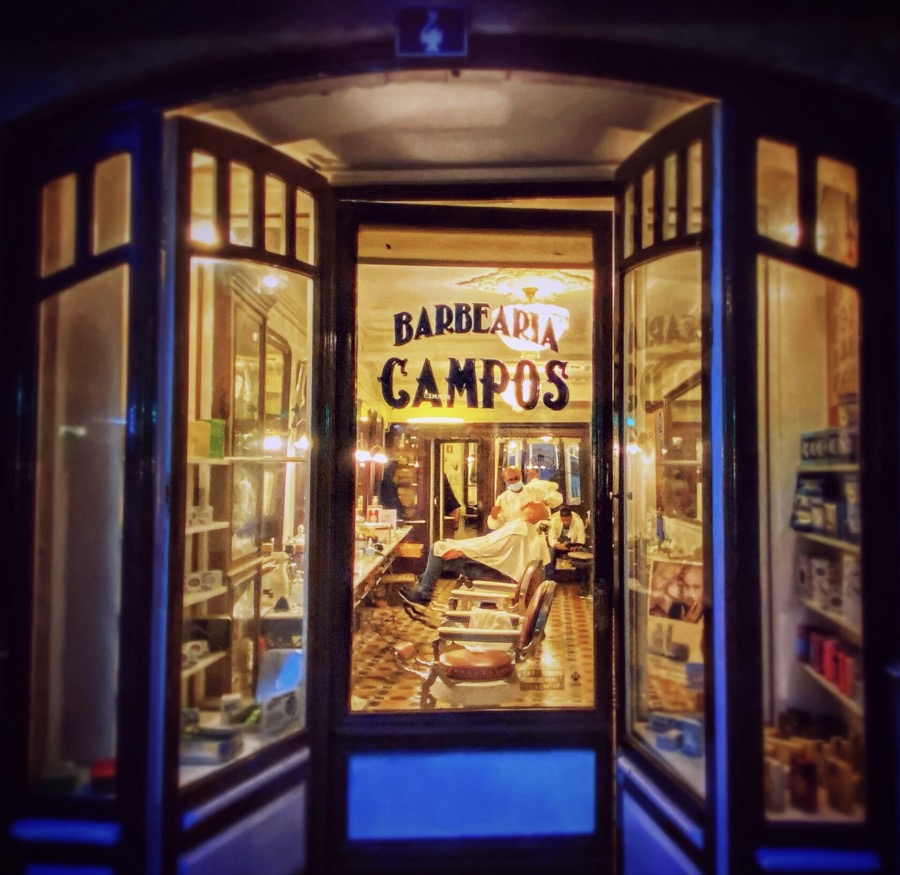 A lit barbershop storefront at night in Lisbon, Portugal