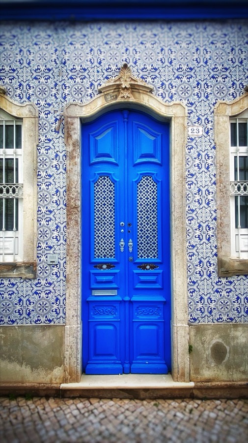 Traditional blue door framed by azulejo tiles on a home in Tavira, Portugal