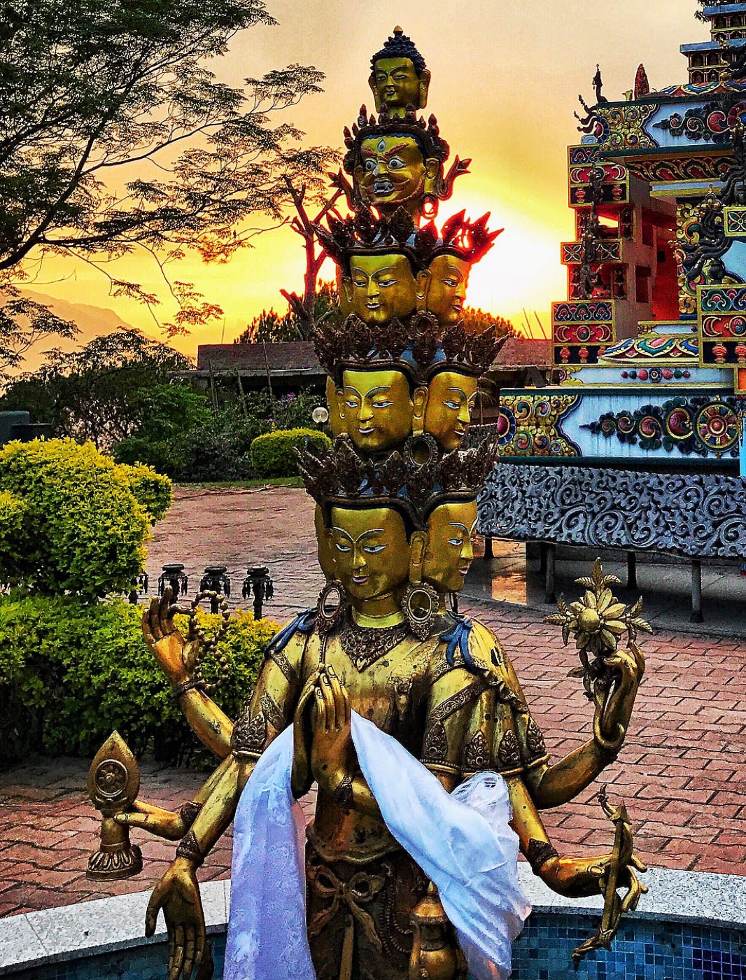A golden multi-headed Buddhist statue at Kopan Monastery at sunset