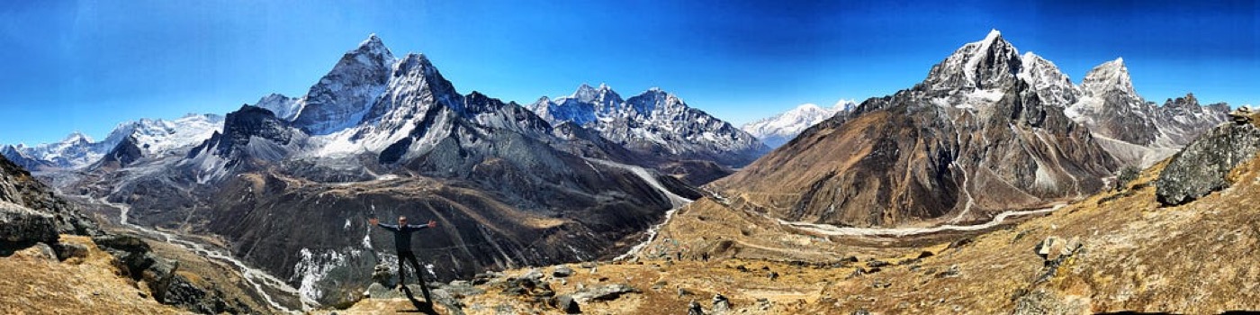 A wide panorama of Himalayan peaks above a rocky valley trail