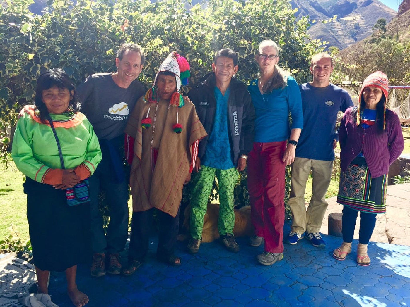 Seven people in ponchos and jackets standing together in a garden
